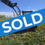 2022-bobcat-l28-small-articulated-loader-sold-western-canada-lifted-bucket-side-view-field