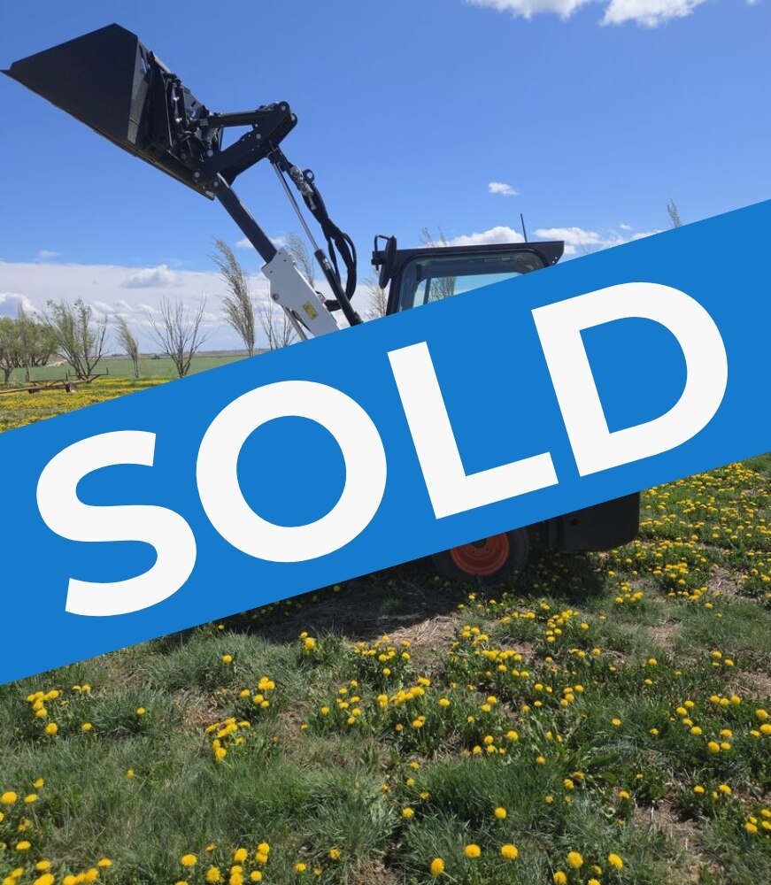 2022-bobcat-l28-small-articulated-loader-sold-western-canada-lifted-bucket-side-view-field