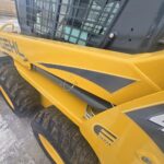 Close-up of the side panel of a Gehl 4640 skid steer loader, displaying G Series branding, hydraulic components, and robust tires. Located in Western Canada, ready for work