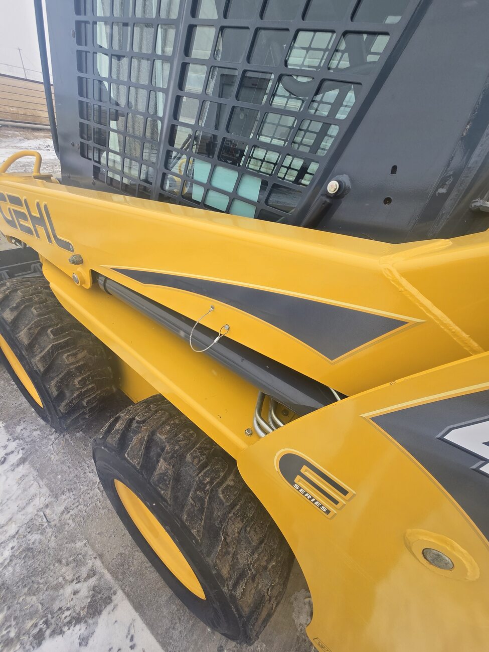 Close-up of the side panel of a Gehl 4640 skid steer loader, displaying G Series branding, hydraulic components, and robust tires. Located in Western Canada, ready for work