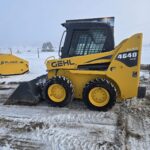 Full side profile of a Gehl 4640 skid steer loader designed for efficient material handling and construction work For sale in Western Canada arctic snow pusher in background