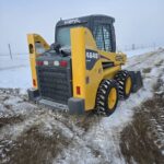 Rear side perspective of a Gehl 4640 skid steer loader on a snowy worksite. Equipped with durable tires and a compact frame, ideal for heavy-duty tasks in Western Canada.jpg