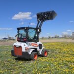 bobcat-l28-2022-loader-rear-angle-lift-arm-up-dandelion-field-western-canada-equipment-sale