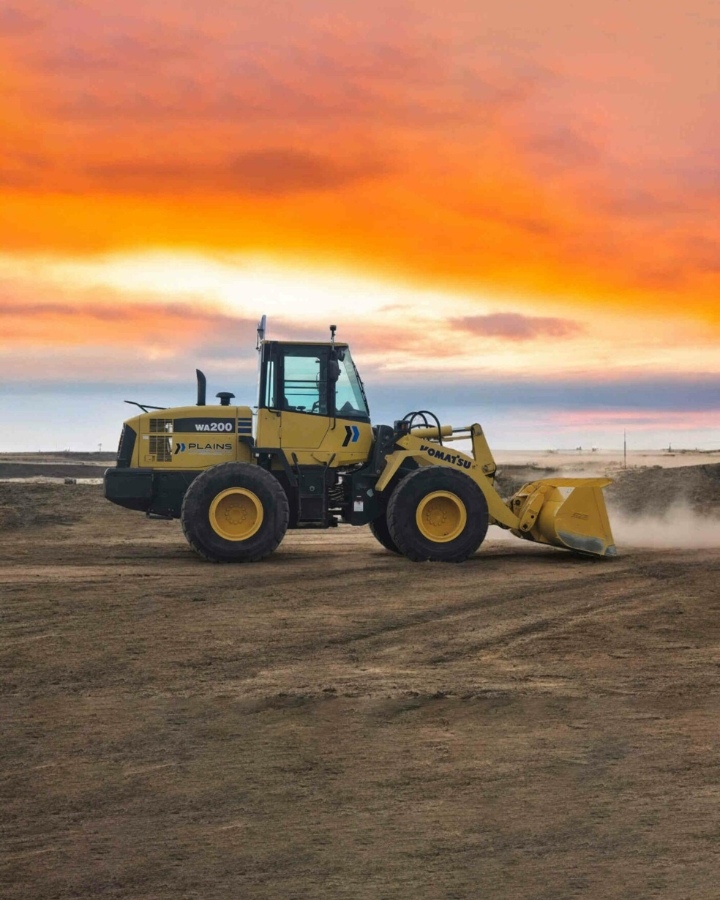 Komatsu-WA200-loader-from-Plains-Equipment-Rentals-operating-in-Western-Canada-set-against-a-vibrant-sunset-on-an-open-construction-site