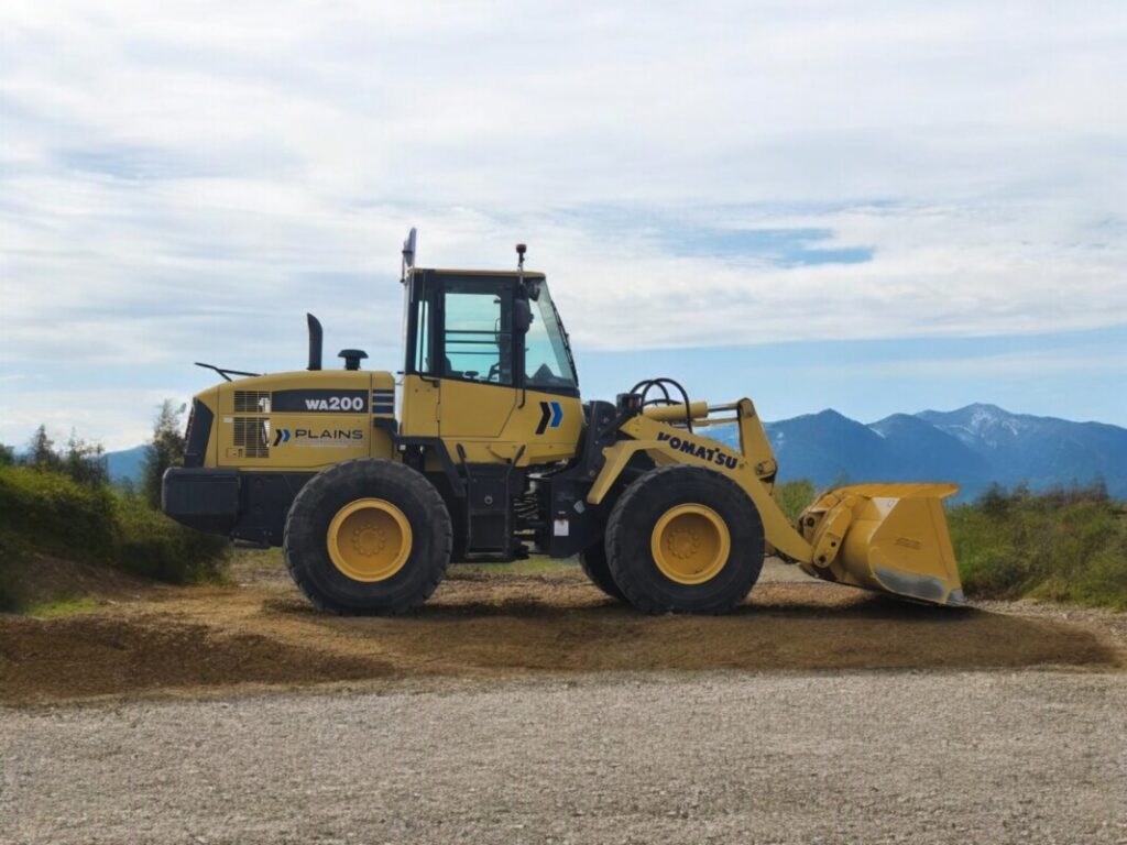 komatsu-wa200-wheel-loader-on-jobsite-mountain-backdrop-plains-equipment-rentals-western-canada