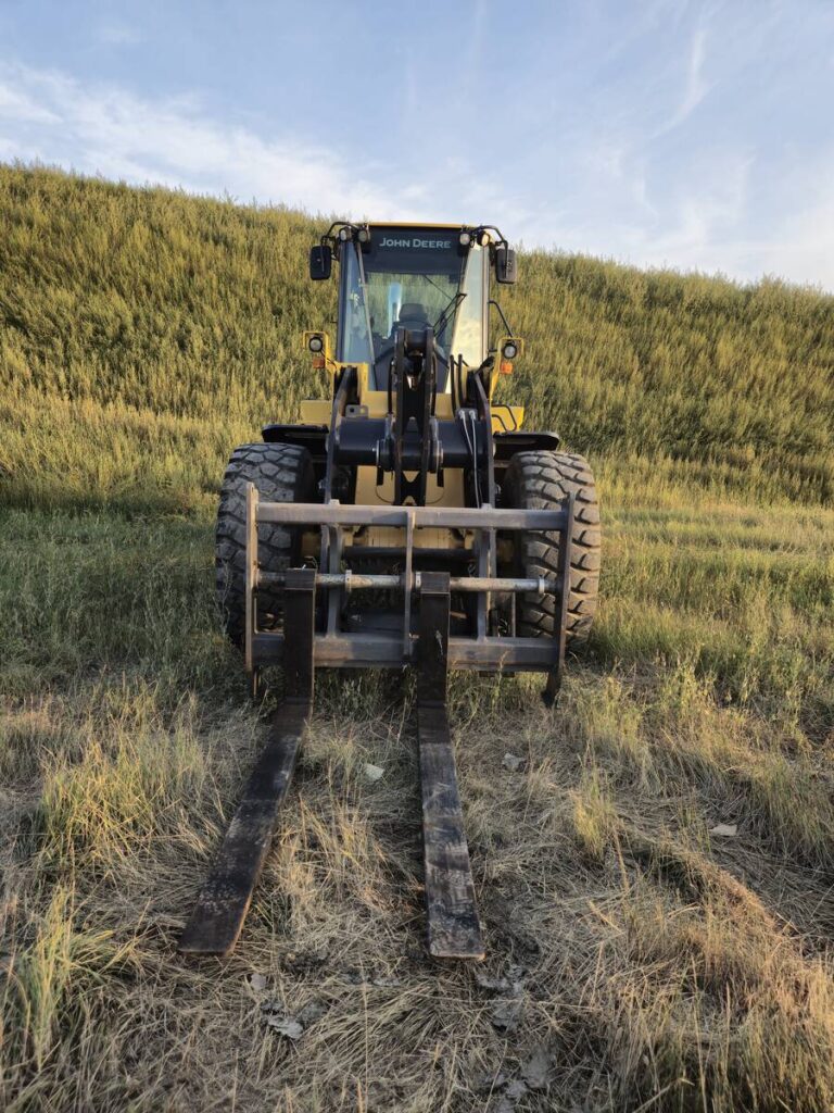 Front view of John Deere 524K-II loader with pallet forks, available for sale in Western Canada
