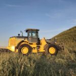 John Deere 524K-II loader photographed in field at sunset, Plains Equipment Rentals Western Canada