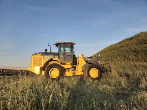 John Deere 524K-II loader photographed in field at sunset, Plains Equipment Rentals Western Canada