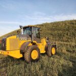 John Deere 524K-II wheel loader for sale, photographed in Western Canada field at sunset