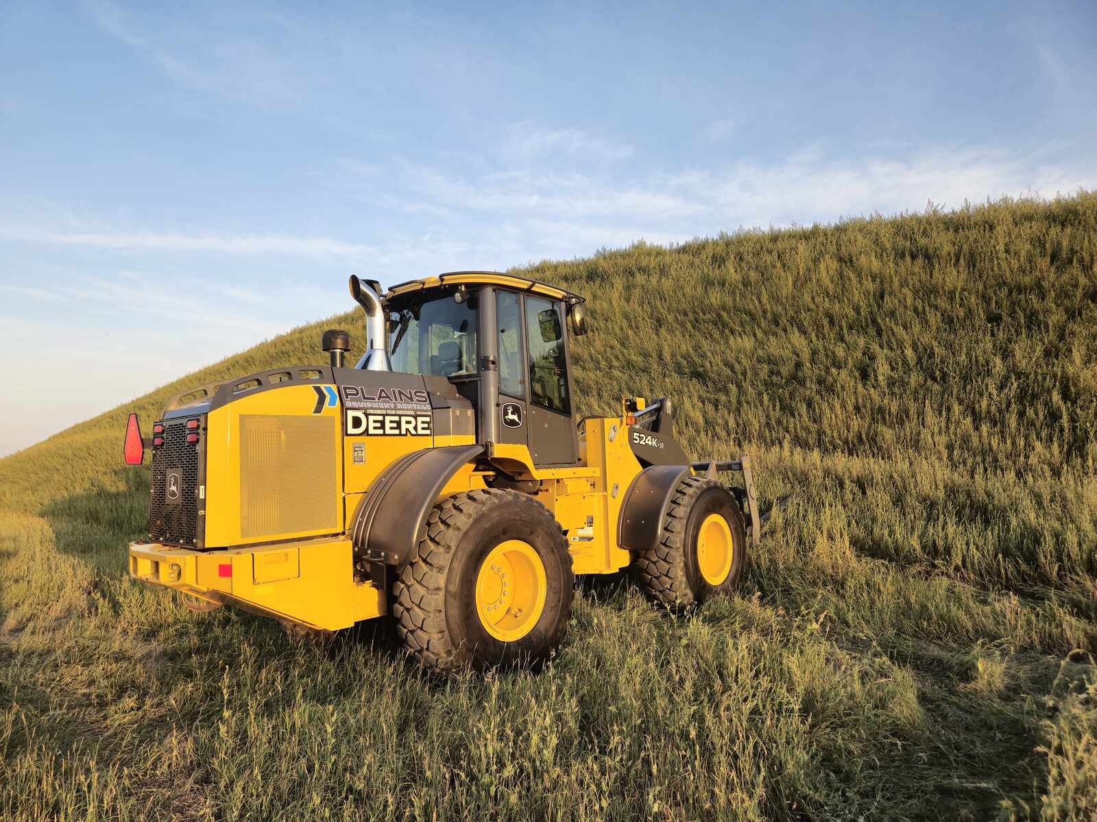 John Deere 524K-II wheel loader for sale, photographed in Western Canada field at sunset