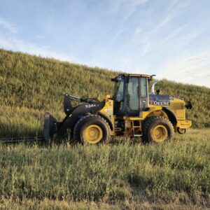 John Deere 524K-II wheel loader with pallet forks from Plains Equipment Rentals in Western Canada for sale, side view in field