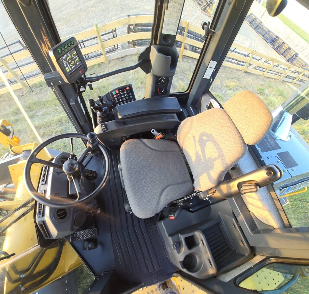 Operator’s cab interior of John Deere 524K-II loader showing steering wheel, seat, and controls