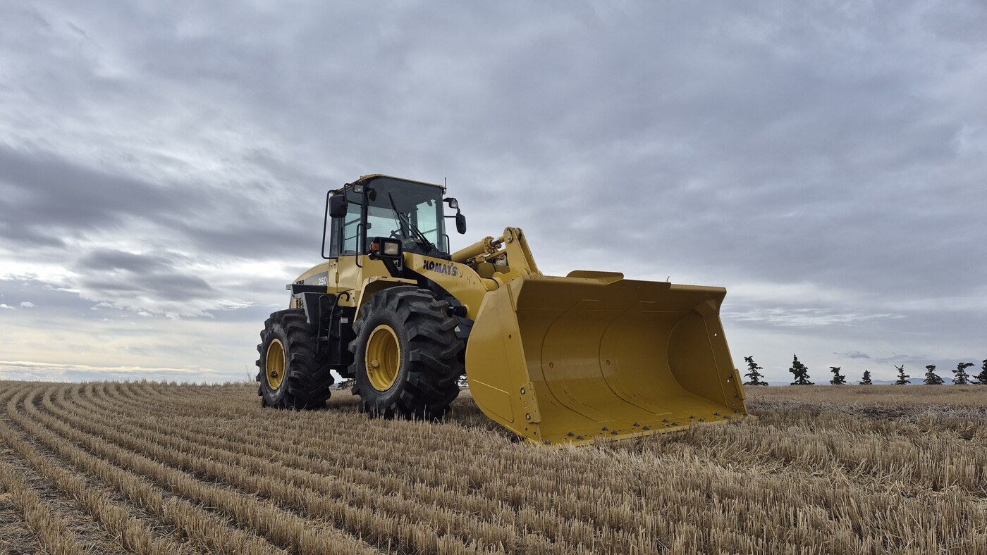 2010 Komatsu WA250-6 side profile parked in Alberta field showing loader arm and bucket