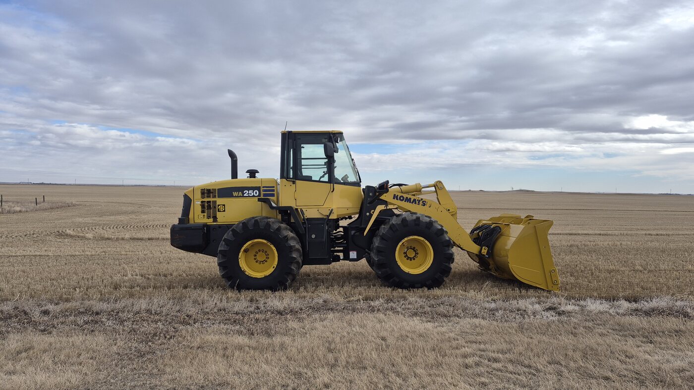 2010 Komatsu WA250-6 wheel loader side view in Alberta field showing overall condition