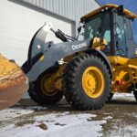 Yellow John Deere 444 wheel loader with snow plow attachment in Western Canada