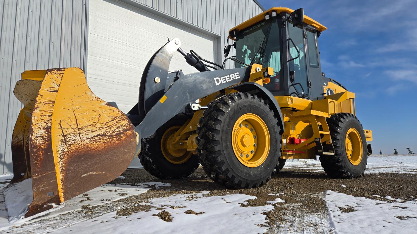 Yellow John Deere 444 wheel loader with snow plow attachment in Western Canada