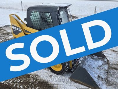 Angled-view-of-a-Gehl-4640-skid-steer-loader-showing-its-protective-cab-tires-with-snow-grip-and-bucket-attachment.-Perfect-for-farming-and-construction-use-in-Western-Canada-sold